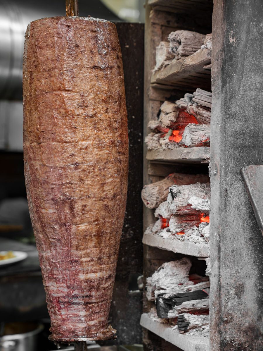 Kebab spit grilling beside glowing charcoal