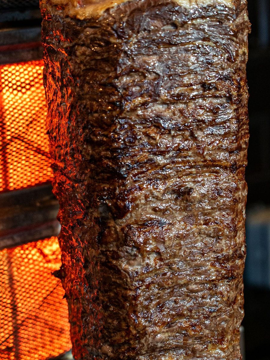Doner kebab meat turning on the spit over open flames